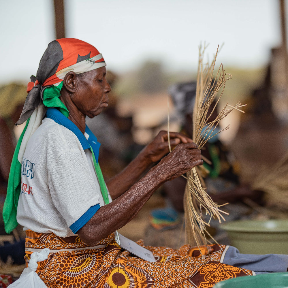 a woman weaving a basket outdoors